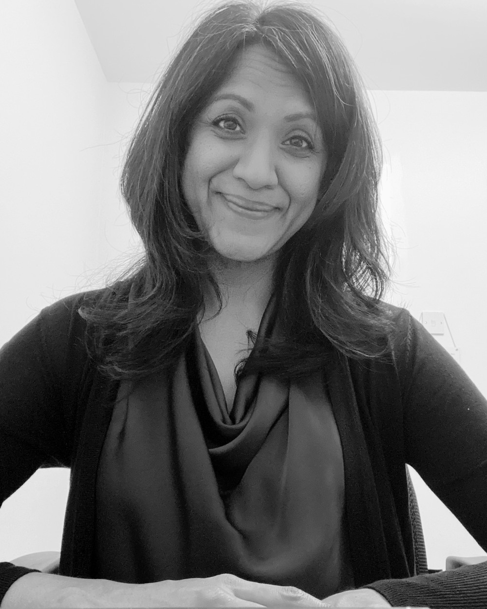 Karoona, smiling, seated at a desk.