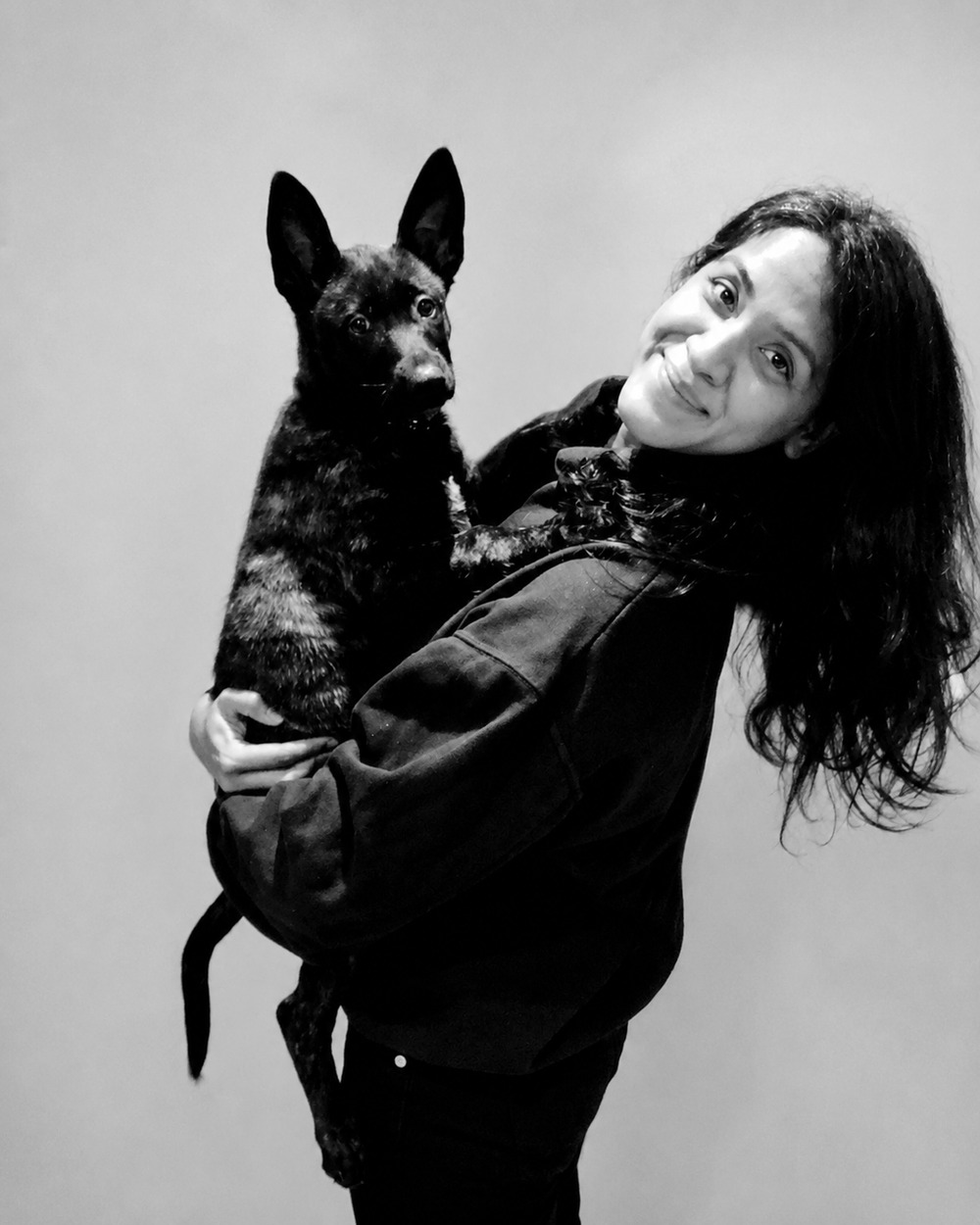 Karoona, smiling, holding her dog in her arms.